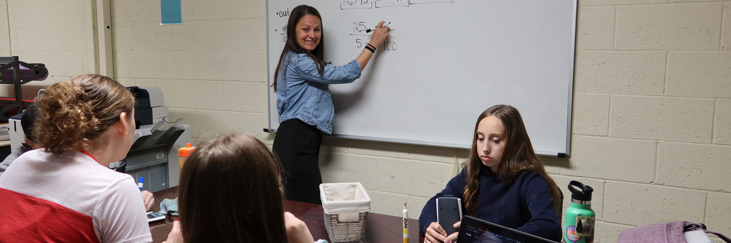 A teacher writing down on a whiteboard.