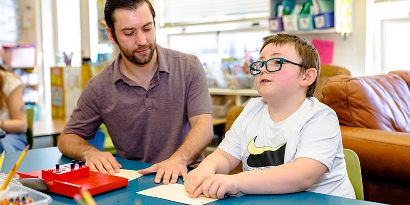 Professor teaching braille reading.